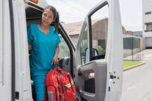 Female medical technician getting out of an ambulance with a first aid bag