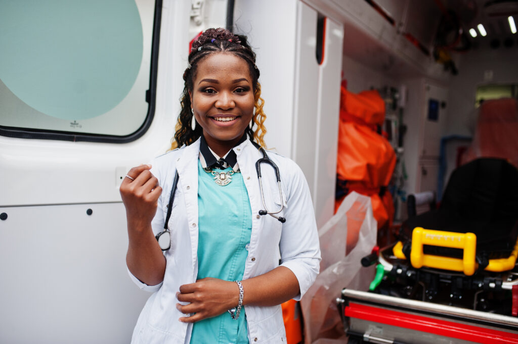 African american female paramedic standing in front of ambulance car.